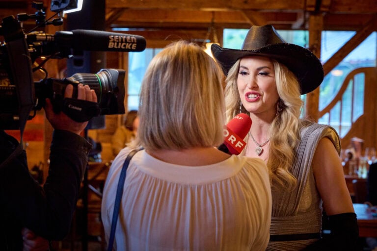 TV-Interview mit Frau in Hut