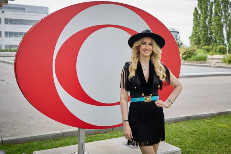 Frau mit Hut vor rotem Symbol im Freien