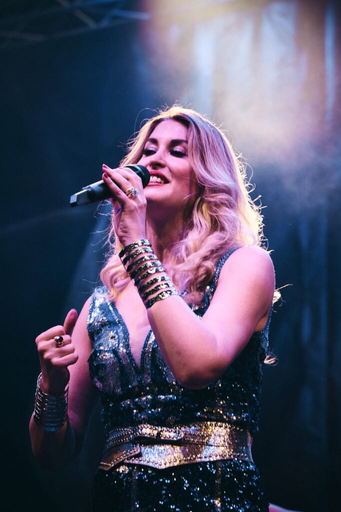 Frau singt auf der Bühne mit Mikrofon