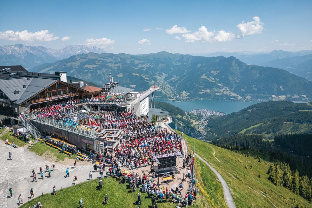 Große Menschenmenge feiert auf einem Bergrestaurant mit Seeblick.